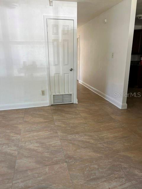 A room with light-colored walls and tan tile flooring features a white louvered closet door — 1227 SE 19TH TERRACE, GAINESVILLE, FL