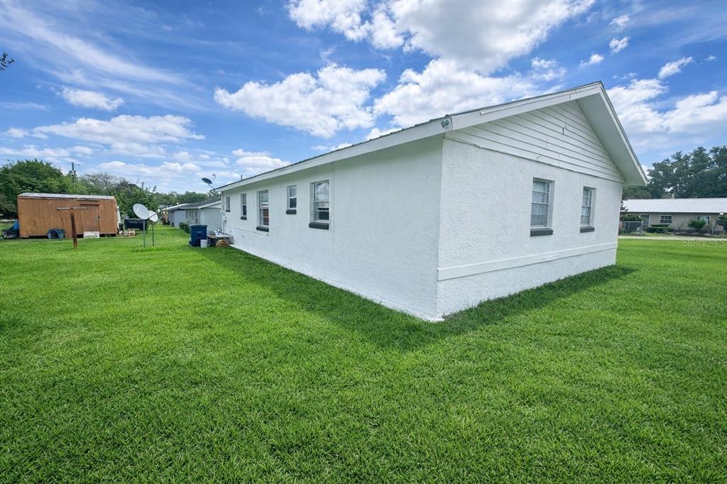 A white, single-story house with a stucco exterior sits on a large, grassy lawn — 1004 BOOKER AVENUE, SEBRING, FL