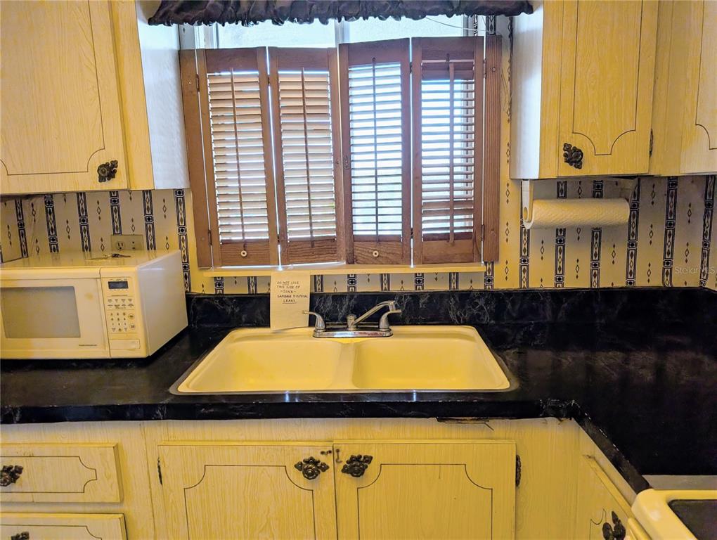 A kitchen sink with a double basin sits below a window with wooden shutters — 3714 LAKE BAYSHORE DRIVE UNIT K-418, BRADENTON, FL