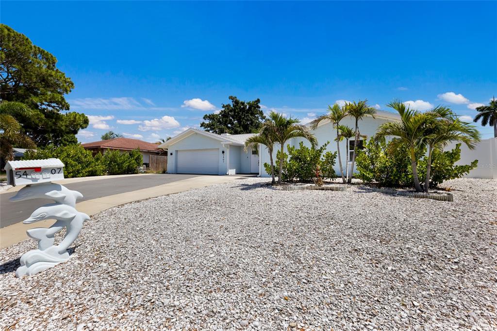 A light-colored house with a gravel front yard and a dolphin-themed mailbox — 5407 2ND AVENUE DRIVE NW, BRADENTON, FL