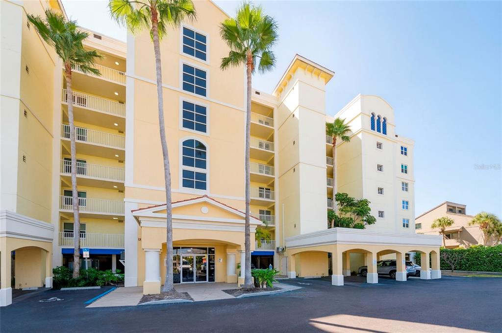 A multi-story yellow apartment building with palm trees and a covered entrance — 16750 GULF BOULEVARD UNIT 311, NORTH REDINGTON BEACH, FL