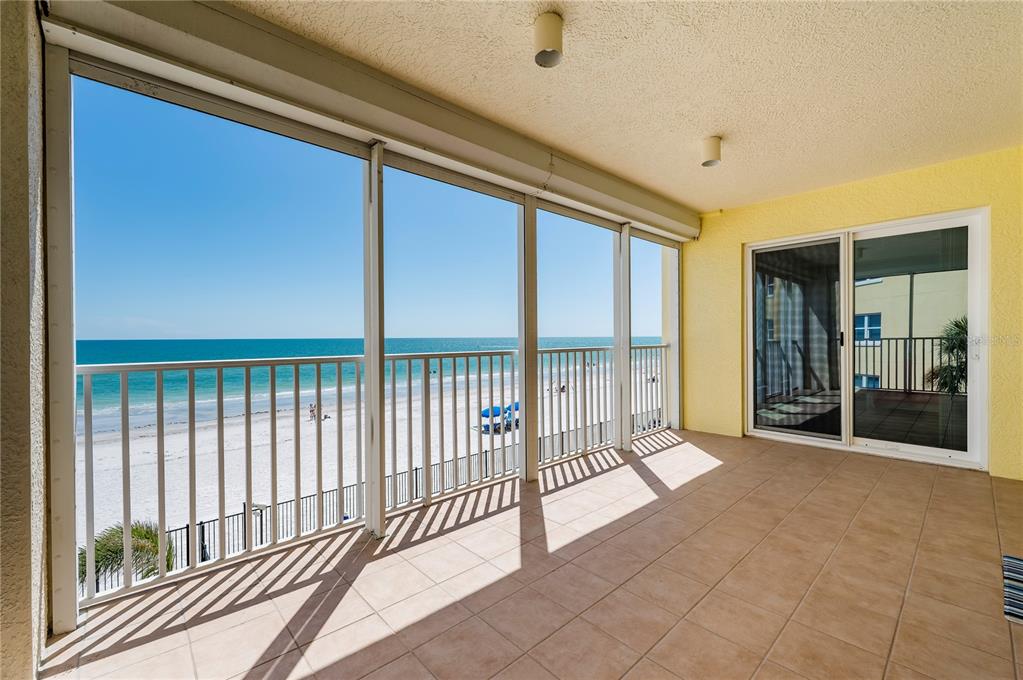 A tiled balcony features a screened-in enclosure overlooking a sandy beach and the ocean — 16750 GULF BOULEVARD UNIT 311, NORTH REDINGTON BEACH, FL