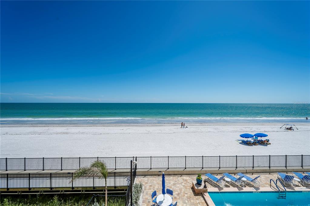 An elevated view of a beach with a swimming pool and lounge chairs in foreground — 16750 GULF BOULEVARD UNIT 311, NORTH REDINGTON BEACH, FL