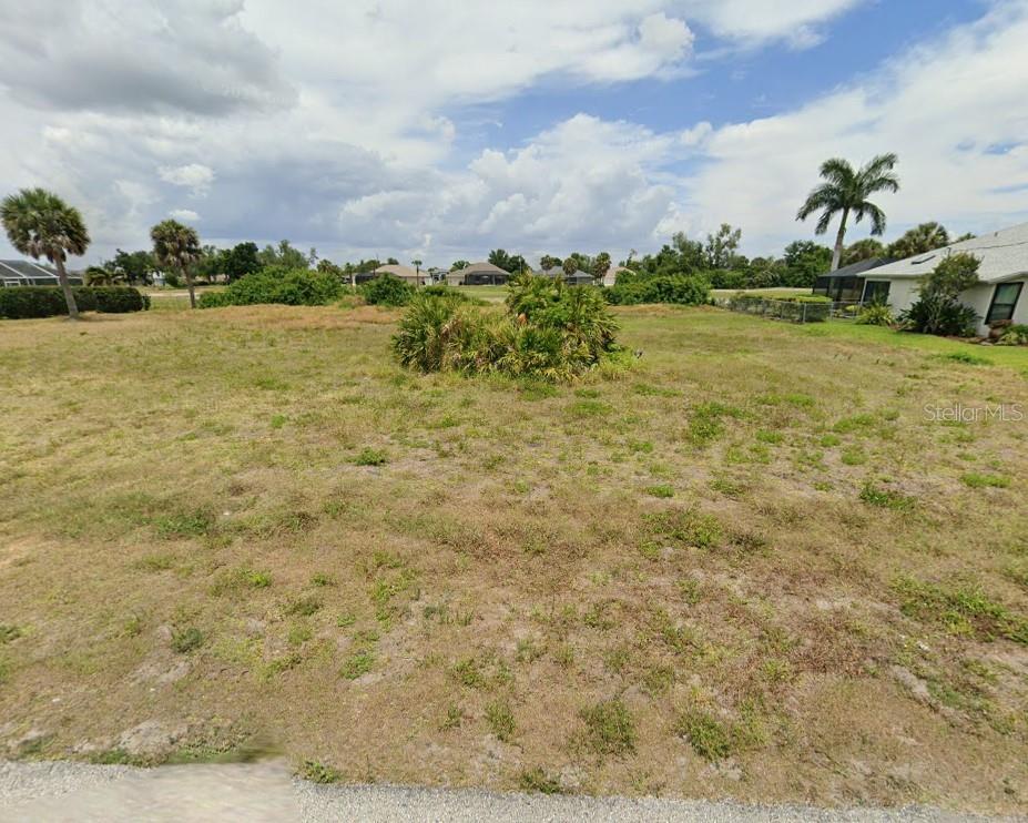 A vacant, grassy residential lot features a central cluster of bushes under a cloudy sky — 66 FAIRWAY ROAD, ROTONDA WEST, FL