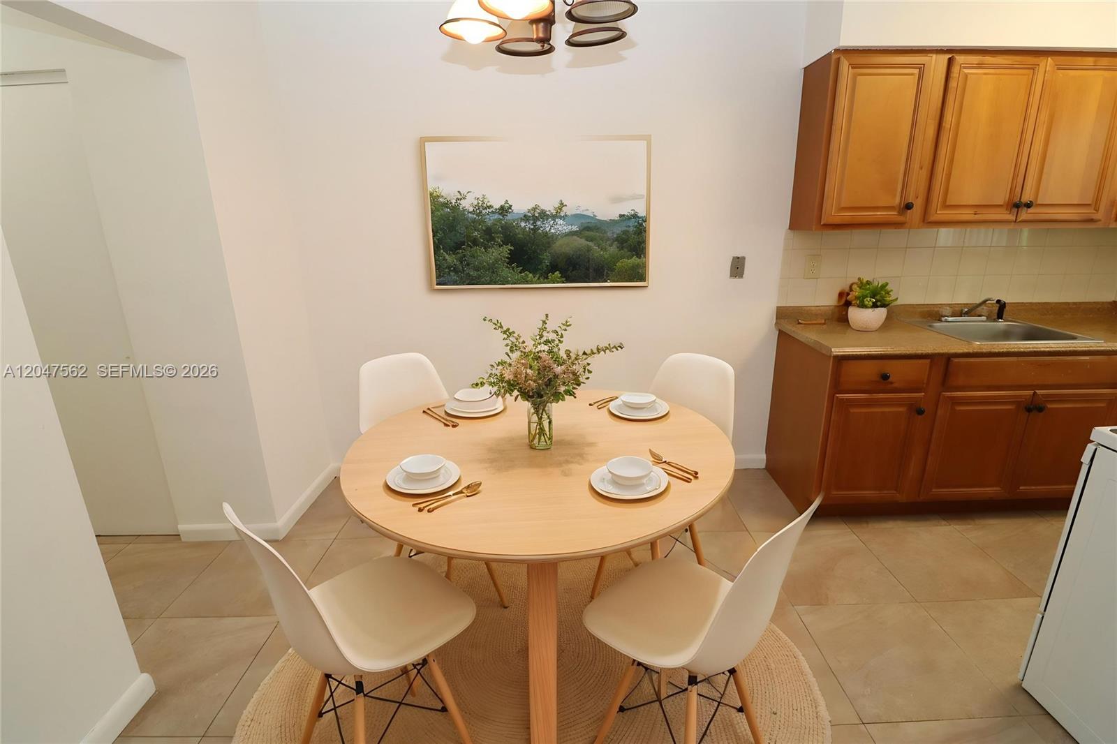A dining area features a round wooden table with four white chairs and a painting — 1708 N 16th Ave # 2, Hollywood FL 33020, HOLLYWOOD, FL