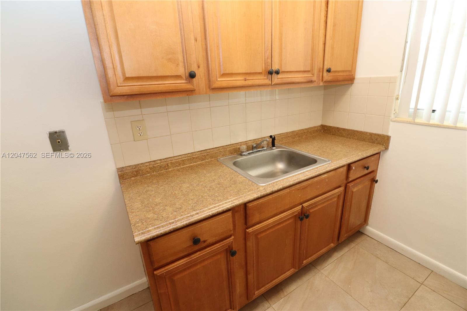 A kitchen features wooden cabinets, a stainless steel sink, and tan laminate countertops — 1708 N 16th Ave # 2, Hollywood FL 33020, HOLLYWOOD, FL