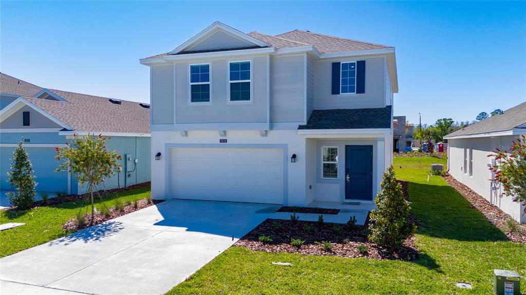 A two-story house with a white garage, blue front door, and light-colored siding — 5858 LE MARIN WAY, KISSIMMEE, FL