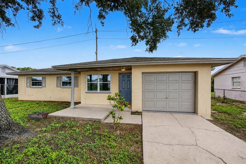 A single-story house with a yellow exterior, a gray garage door, and a concrete driveway — 5608 12TH AVENUE S, TAMPA, FL