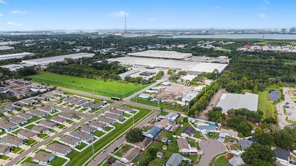 An aerial view shows a residential neighborhood adjacent to a large industrial warehouse complex — 5608 12TH AVENUE S, TAMPA, FL