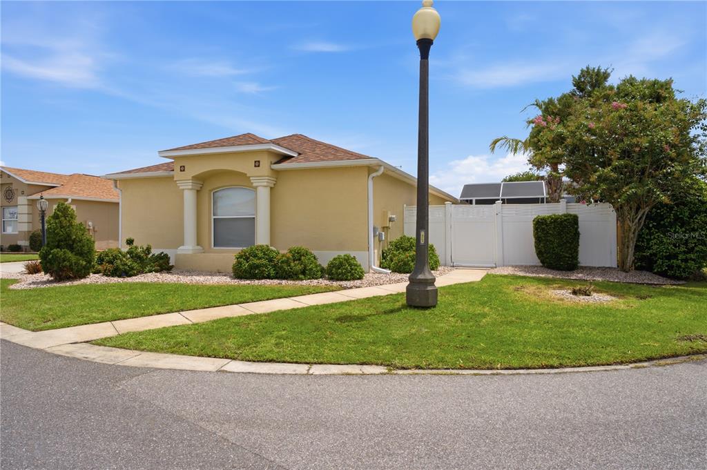 A single-story yellow house with a white fence and a street lamp on the lawn — 2739 ALANDARI LANE, THE VILLAGES, FL