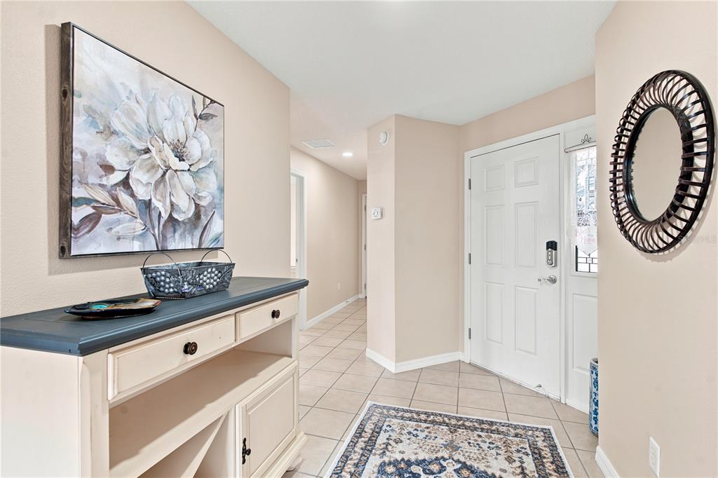 A backyard rock waterfall feature sits in front of a tan wall with two palm trees — 2739 ALANDARI LANE, THE VILLAGES, FL