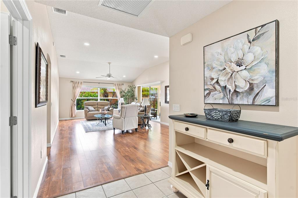 A backyard features a grassy lawn, a rock waterfall, palm trees, and a beige house — 2739 ALANDARI LANE, THE VILLAGES, FL