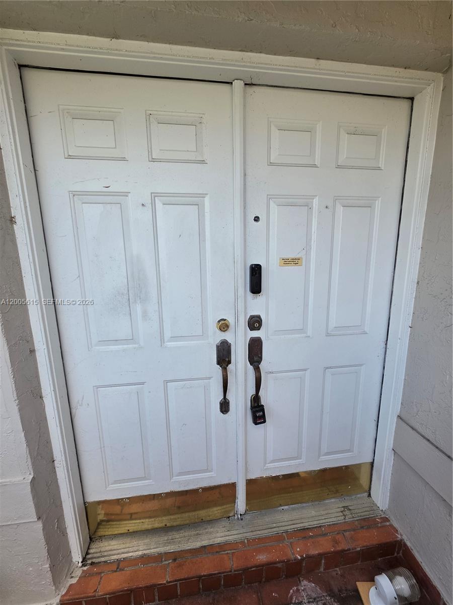 A pair of white double doors with hardware and a lockbox are set in a frame — 5335 SW 153rd Ave, Miami FL 33185, MIAMI, FL