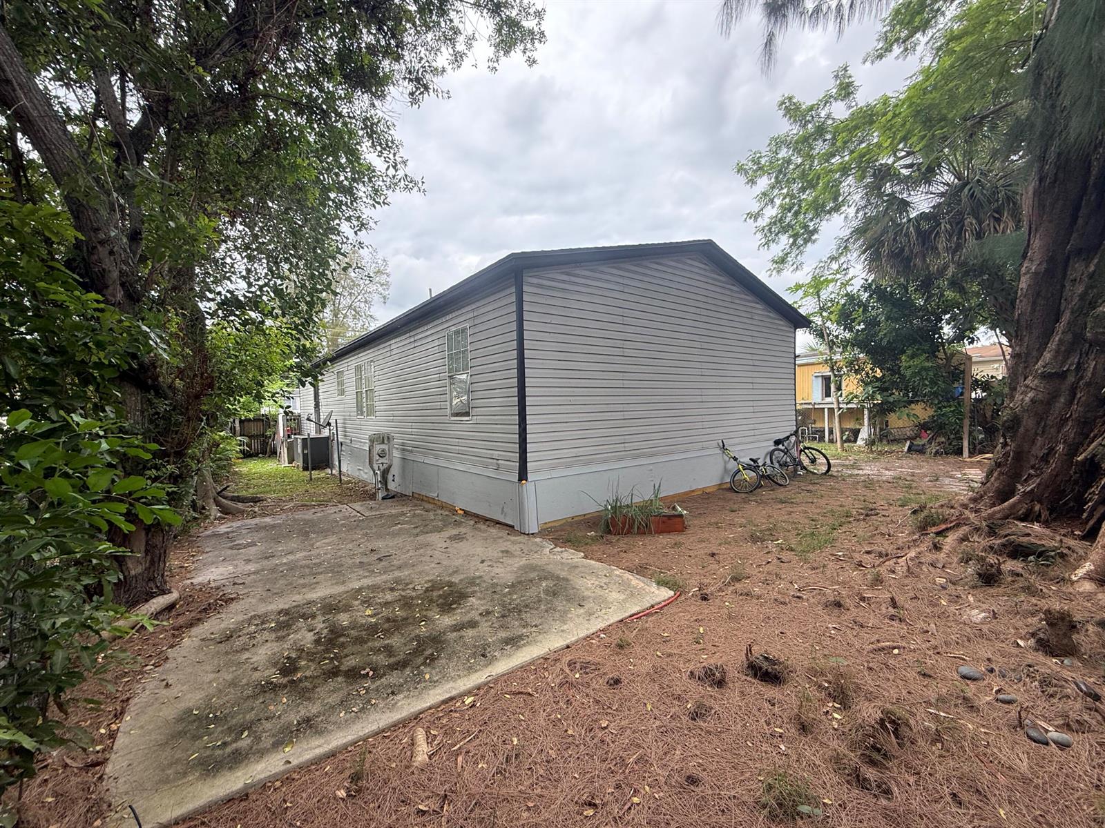 The exterior of a light gray manufactured home sits on a lot with trees — 10548 W Sandalfoot Blvd, FL 33428, FL