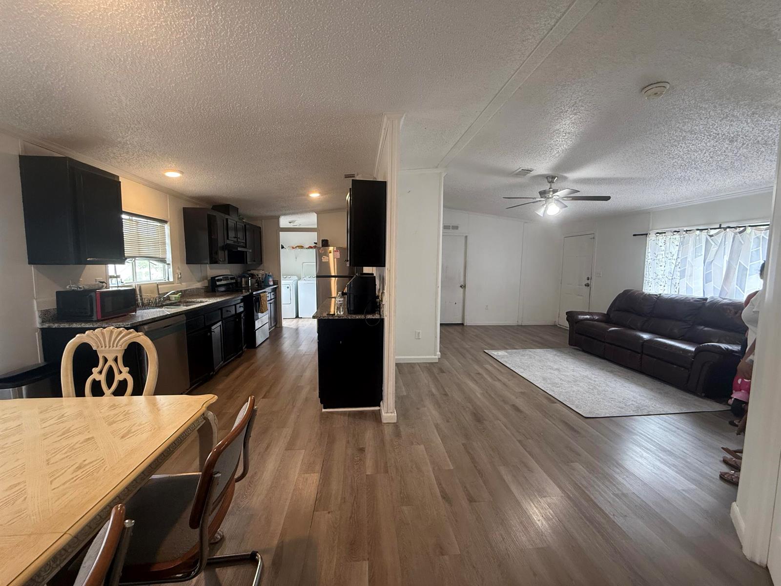 An open-concept kitchen and living area feature dark cabinetry, wood-look flooring, and a ceiling fan — 10548 W Sandalfoot Blvd, FL 33428, FL