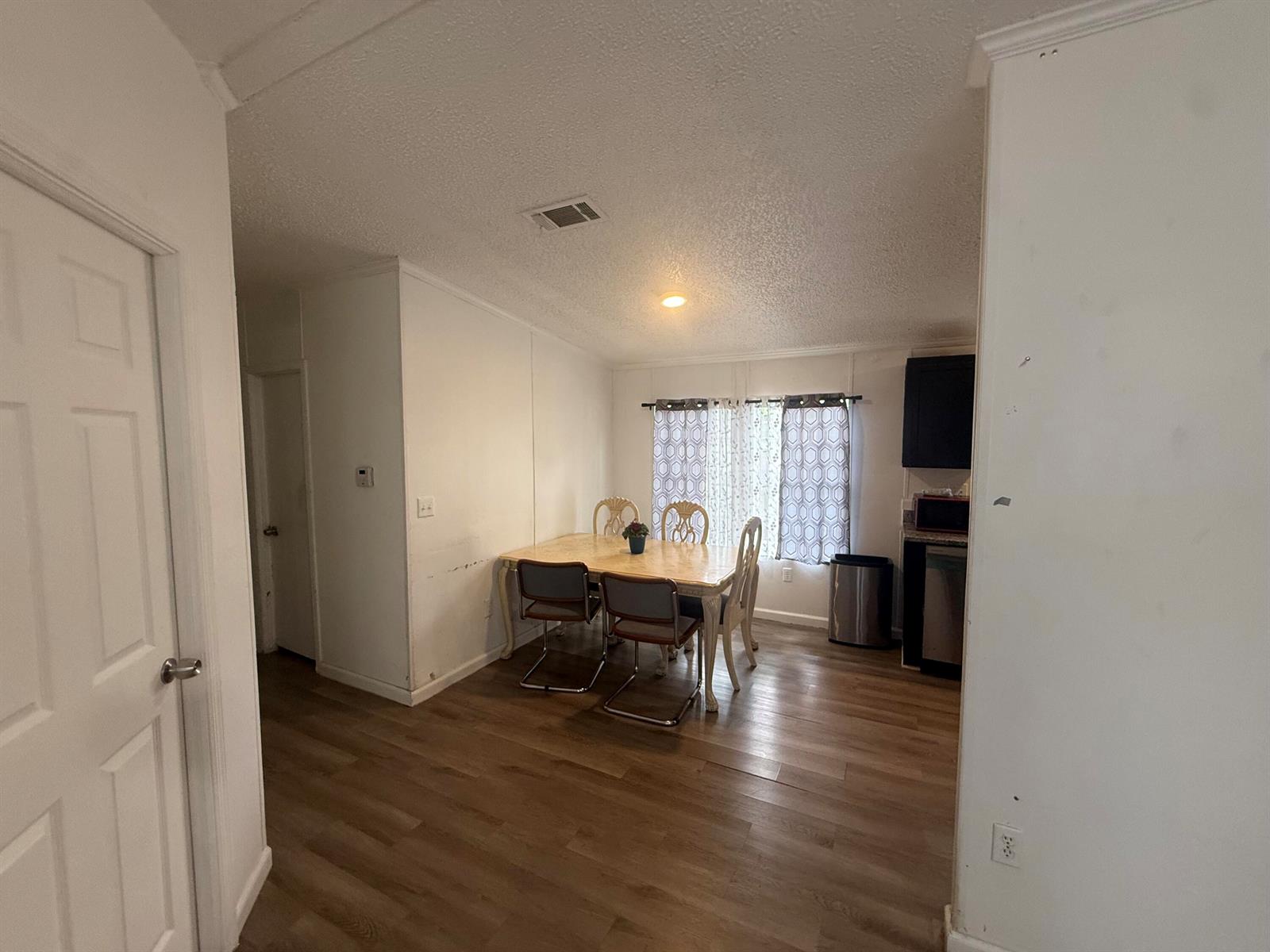 A dining area with wood-look flooring, a table with four chairs, and a window — 10548 W Sandalfoot Blvd, FL 33428, FL