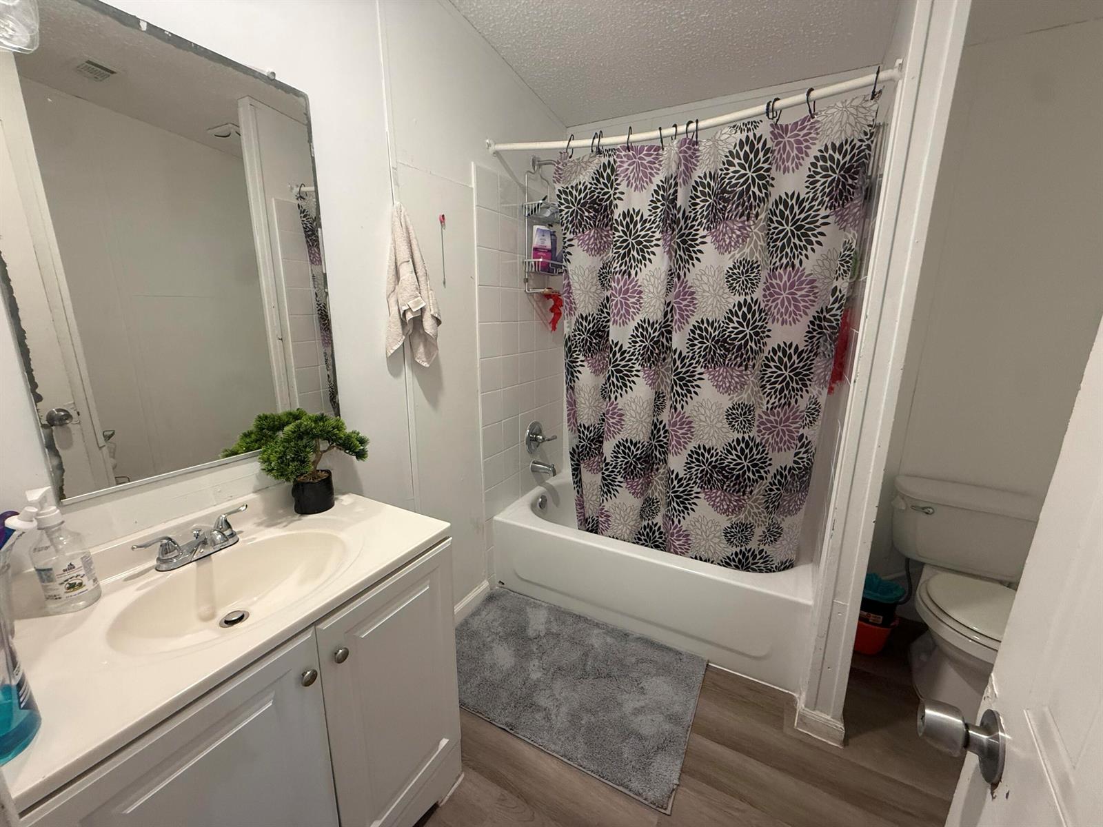 A bathroom features a white vanity, a tub-shower combo with a floral curtain, and flooring — 10548 W Sandalfoot Blvd, FL 33428, FL