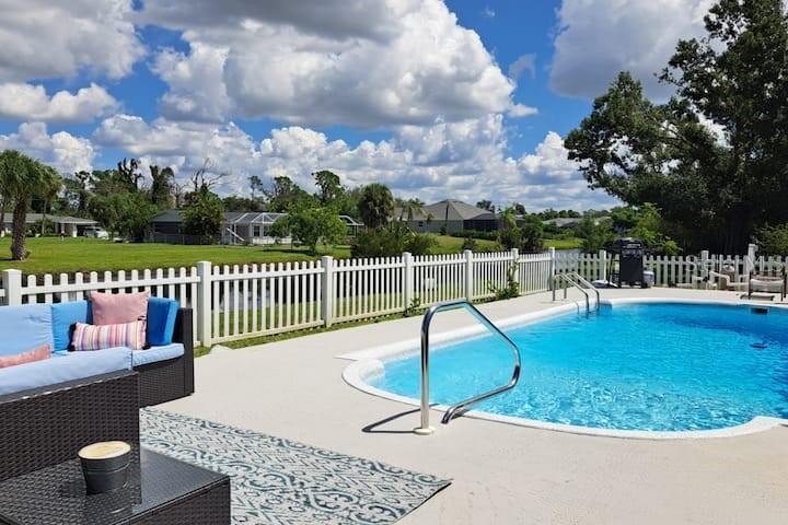A backyard patio features a swimming pool, white picket fence, and outdoor wicker furniture — 231 CADDY ROAD, ROTONDA WEST, FL