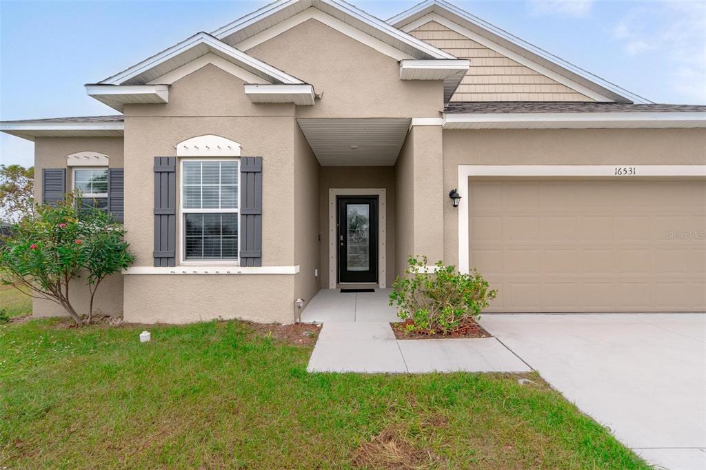 A single-story house exterior features a tan stucco facade, a garage, and a front entrance — 16531 BECASSE DRIVE, PUNTA GORDA, FL