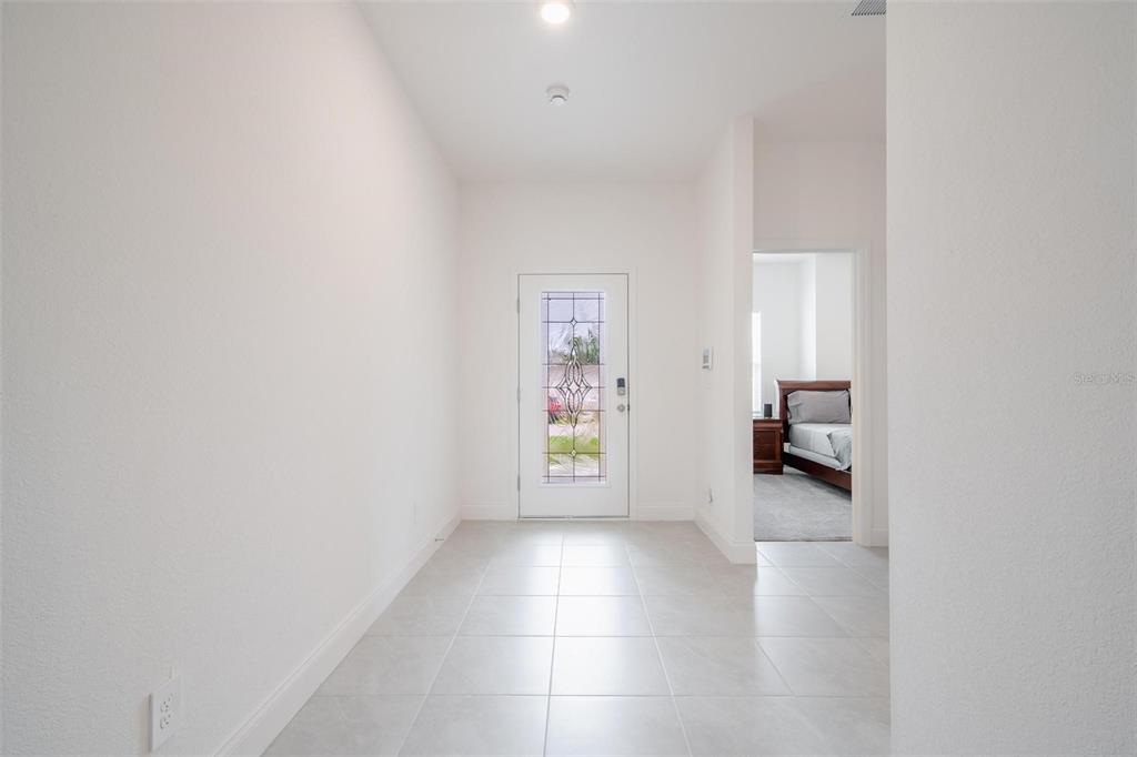 A bright entryway with white walls, light tile flooring, and a glass-paneled front door — 16531 BECASSE DRIVE, PUNTA GORDA, FL