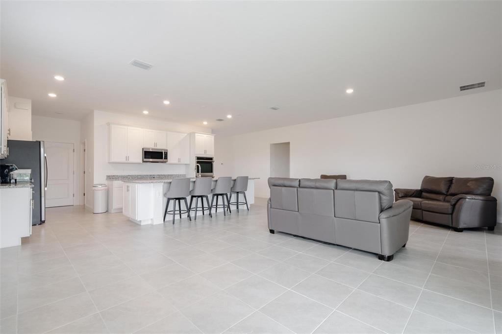An open-concept kitchen and living area features white cabinetry, a kitchen island, and gray furniture — 16531 BECASSE DRIVE, PUNTA GORDA, FL