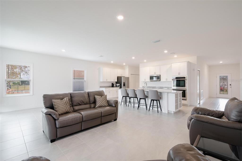 A living room with a grey sofa faces an open kitchen featuring white cabinetry — 16531 BECASSE DRIVE, PUNTA GORDA, FL