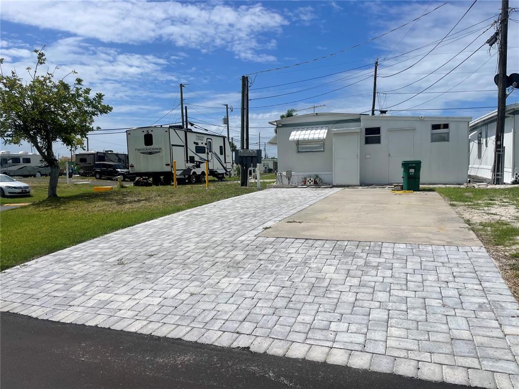 A paved driveway leads to a small mobile home with a green trash bin outside — 47 ILLINOIS STREET, PALMETTO, FL