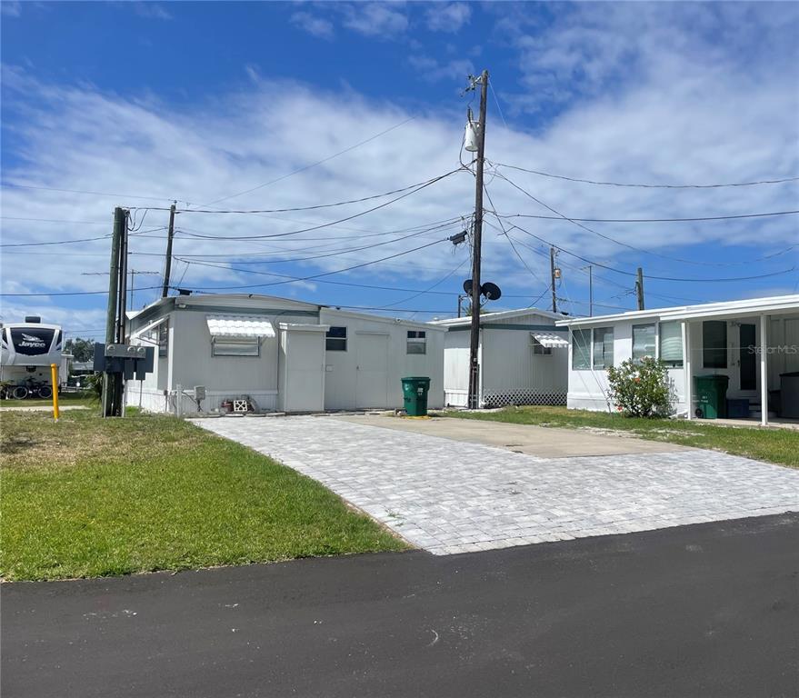 A light-colored mobile home with a paved driveway and a green trash bin outside — 47 ILLINOIS STREET, PALMETTO, FL