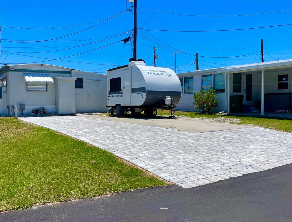 A travel trailer is parked on a paved driveway between two manufactured homes — 47 ILLINOIS STREET, PALMETTO, FL