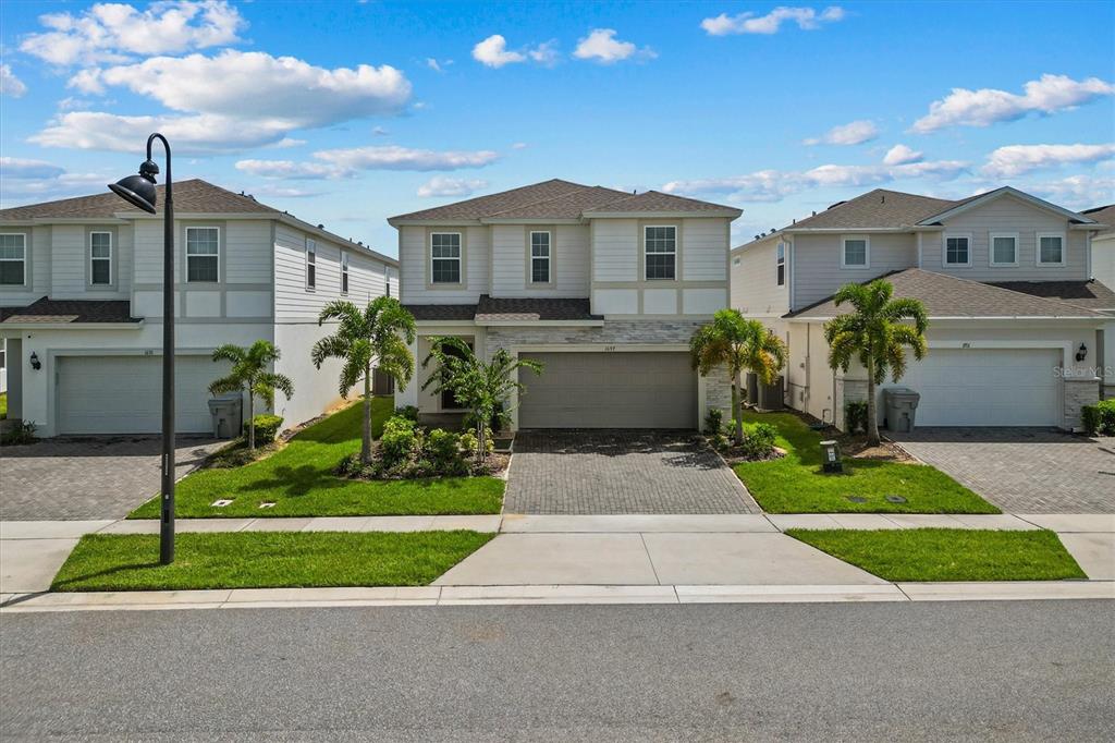 A two-story suburban house with a paved driveway, a two-car garage, and palm trees — 1697 KONA LANE, DAVENPORT, FL