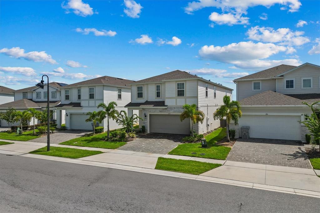 A street view of three two-story suburban houses with paved driveways and palm trees — 1697 KONA LANE, DAVENPORT, FL