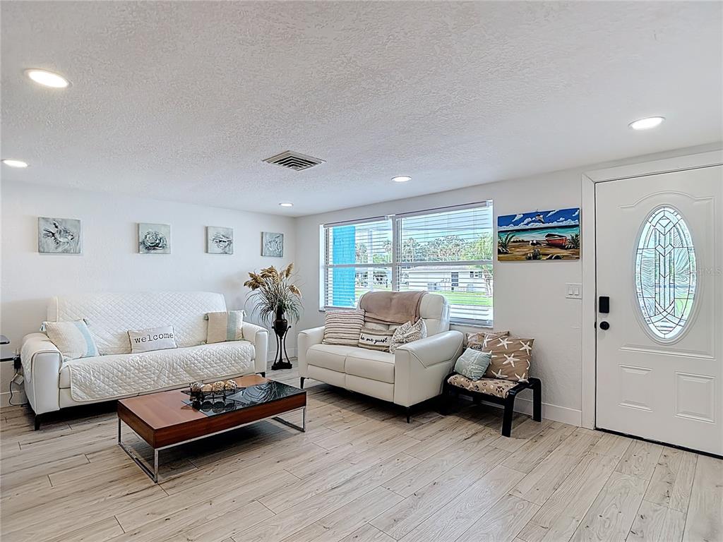 A living room features white furniture, a wood coffee table, and light wood-look flooring — 4462 RUDDER WAY, NEW PORT RICHEY, FL