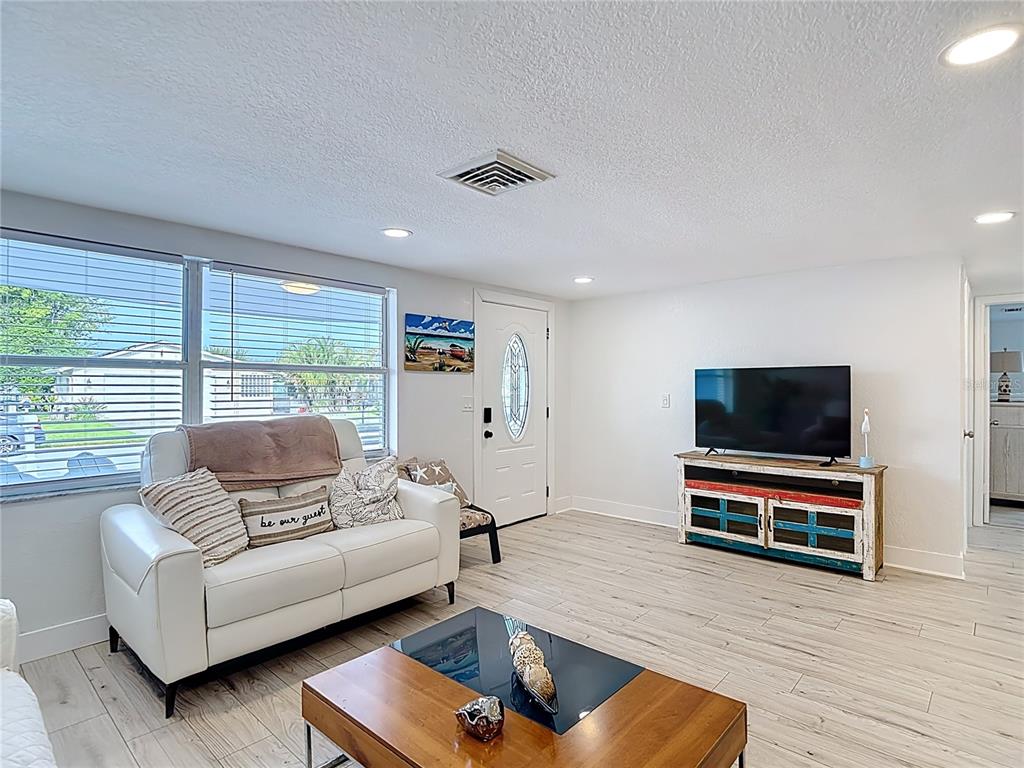 A living room features a white sofa, a wooden coffee table, and a colorful media console — 4462 RUDDER WAY, NEW PORT RICHEY, FL