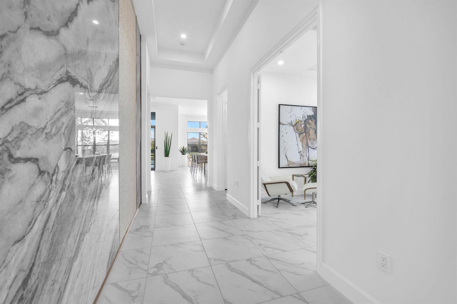 A bright hallway with white marble-look tile flooring leads toward an open-concept living area — 9651 Spruce Woods Drive, Boynton Beach FL 33473, BOYNTON BEACH, FL