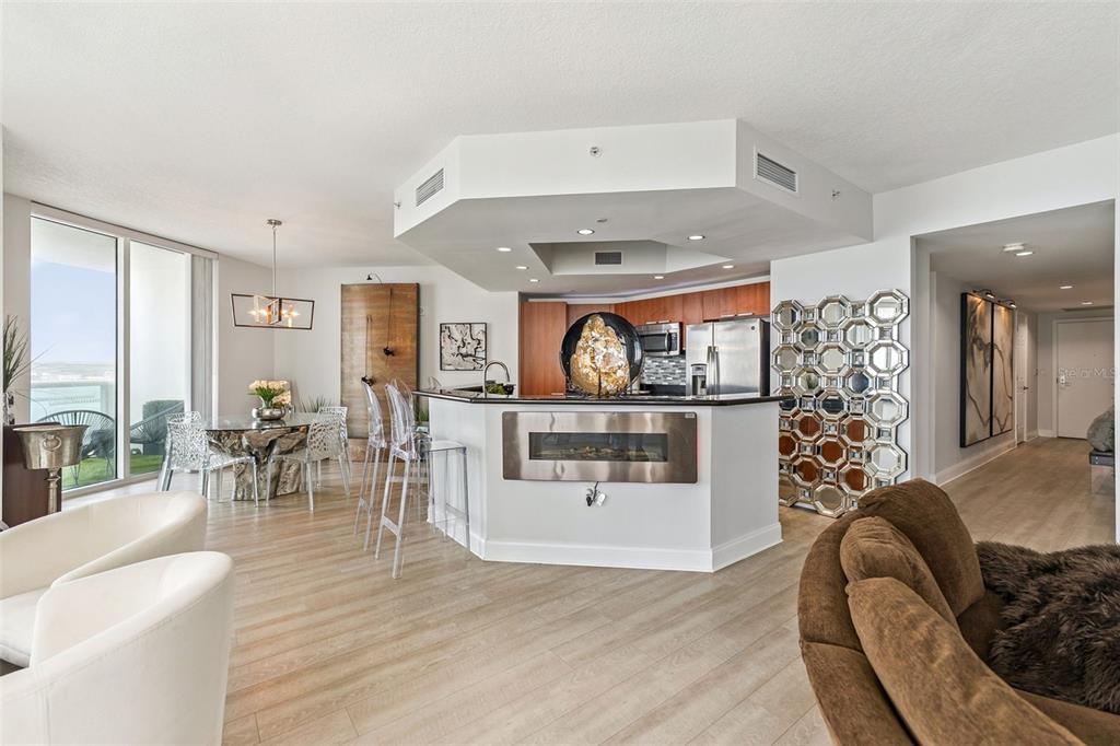 A modern open-concept kitchen and dining area features a fireplace island and glass chairs — 231 RIVERSIDE DRIVE UNIT 702-1, HOLLY HILL, FL