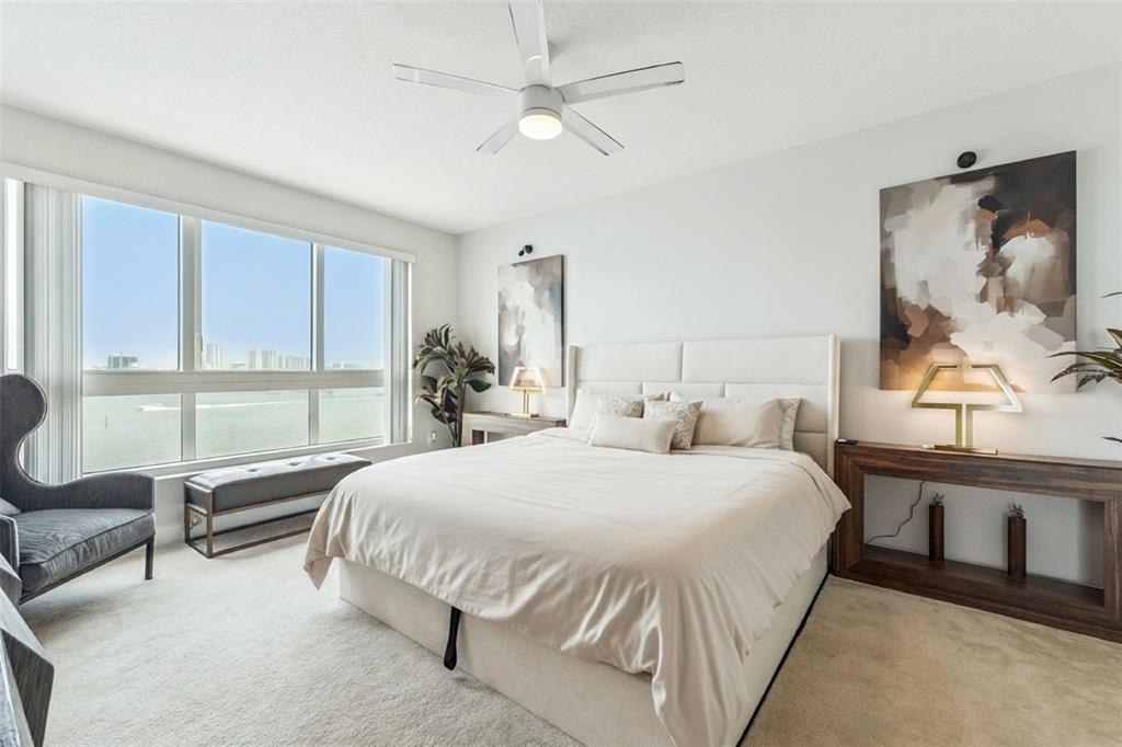 A bedroom features a bed, two console tables, wall art, and a large window view — 231 RIVERSIDE DRIVE UNIT 702-1, HOLLY HILL, FL