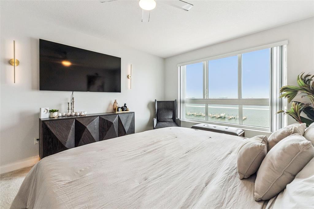 A bedroom features a large bed, a dark geometric dresser, and a waterfront window view — 231 RIVERSIDE DRIVE UNIT 702-1, HOLLY HILL, FL