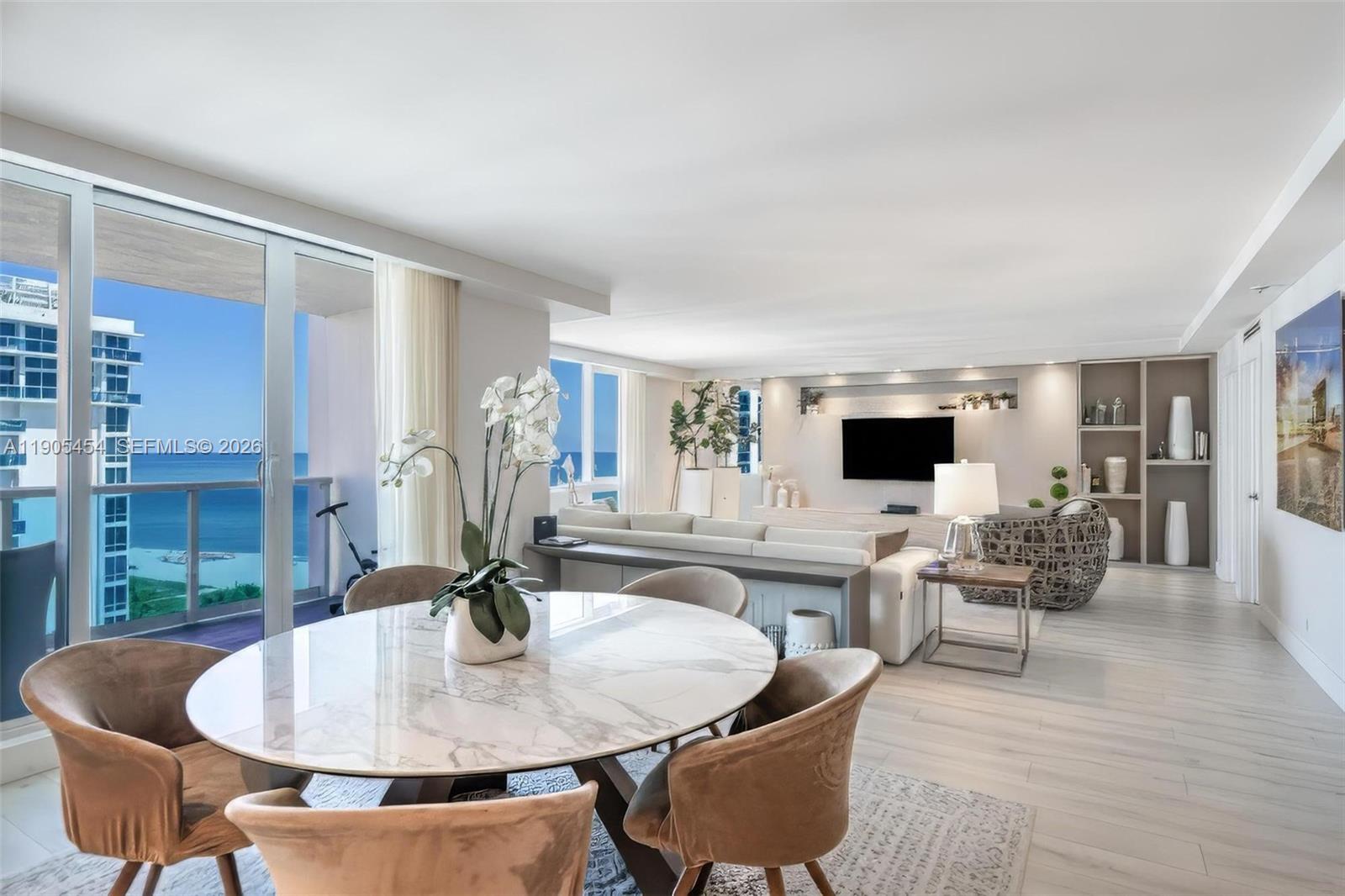 A bright living and dining area features a marble table, ocean views, and neutral decor — 2301 Collins Ave, Miami Beach FL 33139, MIAMI BEACH, FL
