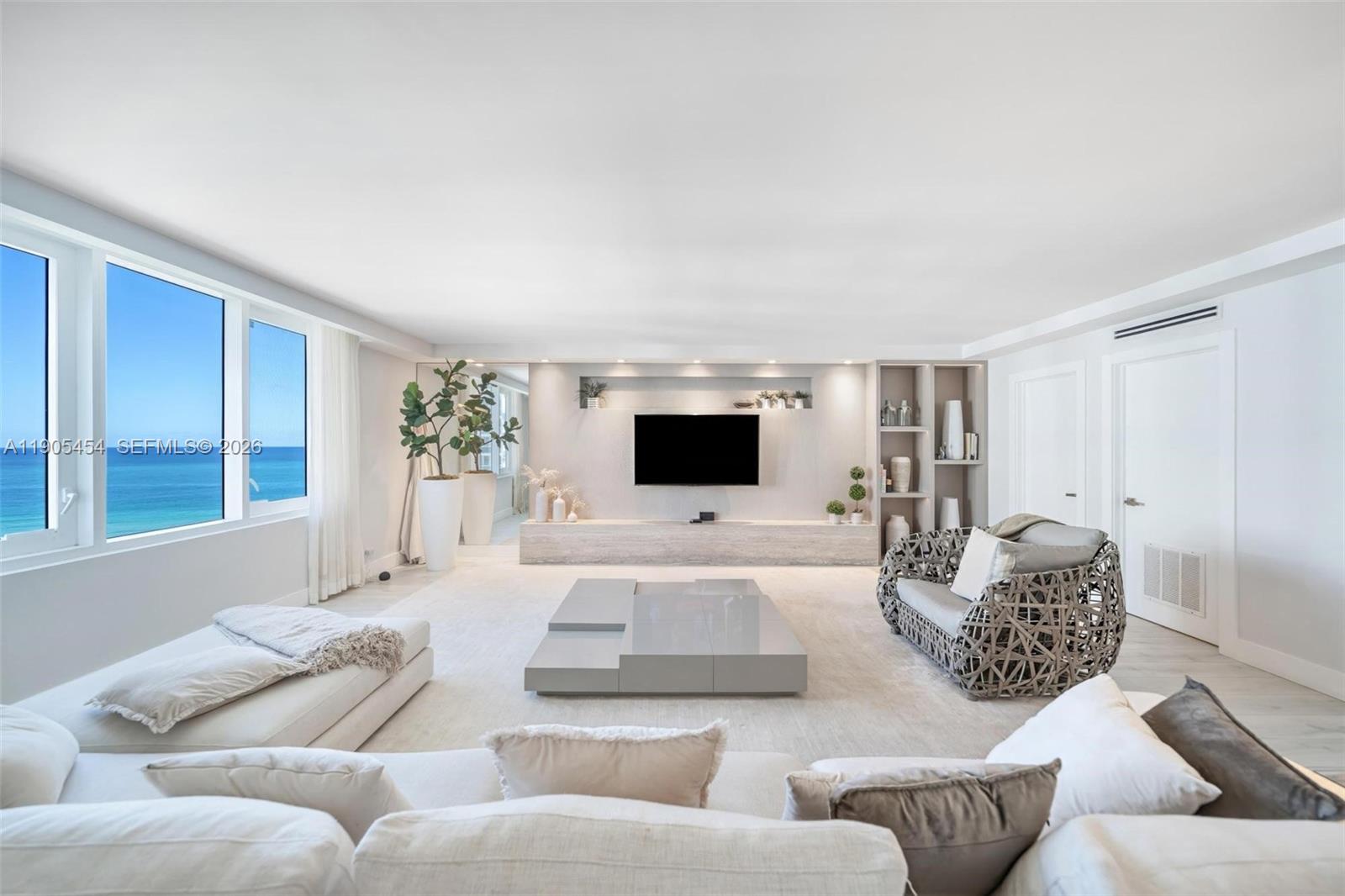A bright living room features a wall-mounted television, modern furniture, and ocean views — 2301 Collins Ave, Miami Beach FL 33139, MIAMI BEACH, FL