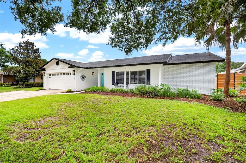 A covered front porch features a turquoise door, white columns, and two black metal chairs — 722 S RANGER BOULEVARD, WINTER PARK, FL