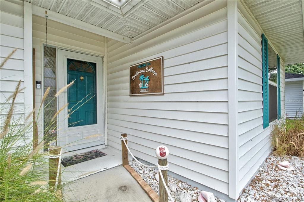 The exterior of a house features white siding, a teal front door, and nautical-themed decor — 1019 SNEAD AVENUE, SARASOTA, FL