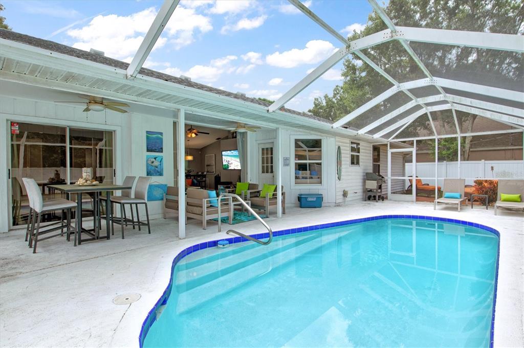 A screened-in patio features a swimming pool, outdoor dining area, and lounge seating — 1019 SNEAD AVENUE, SARASOTA, FL