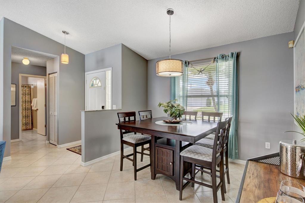 A dining room features a dark wood table with chairs, tile flooring, and a pendant light — 1019 SNEAD AVENUE, SARASOTA, FL