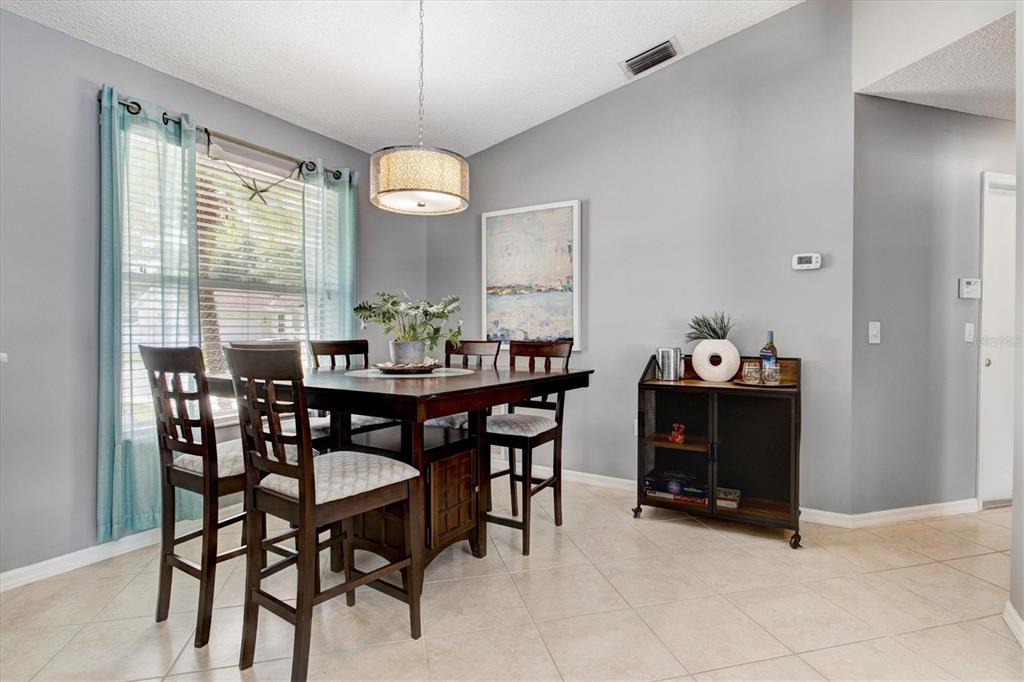A dining room features a dark wood table with chairs, a pendant light, and tile flooring — 1019 SNEAD AVENUE, SARASOTA, FL