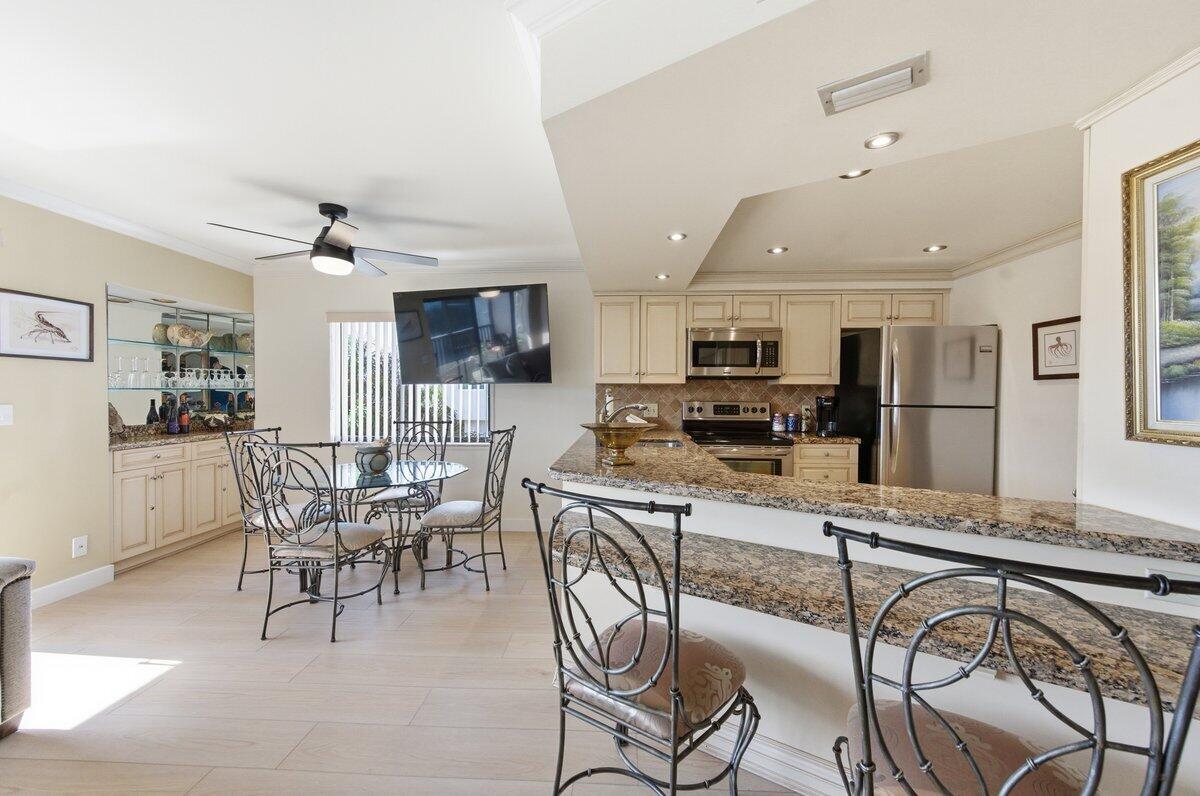 A kitchen with granite countertops and stainless steel appliances opens to a dining area — 1605 S Us Highway 1 # A408, Jupiter FL 33477, JUPITER, FL