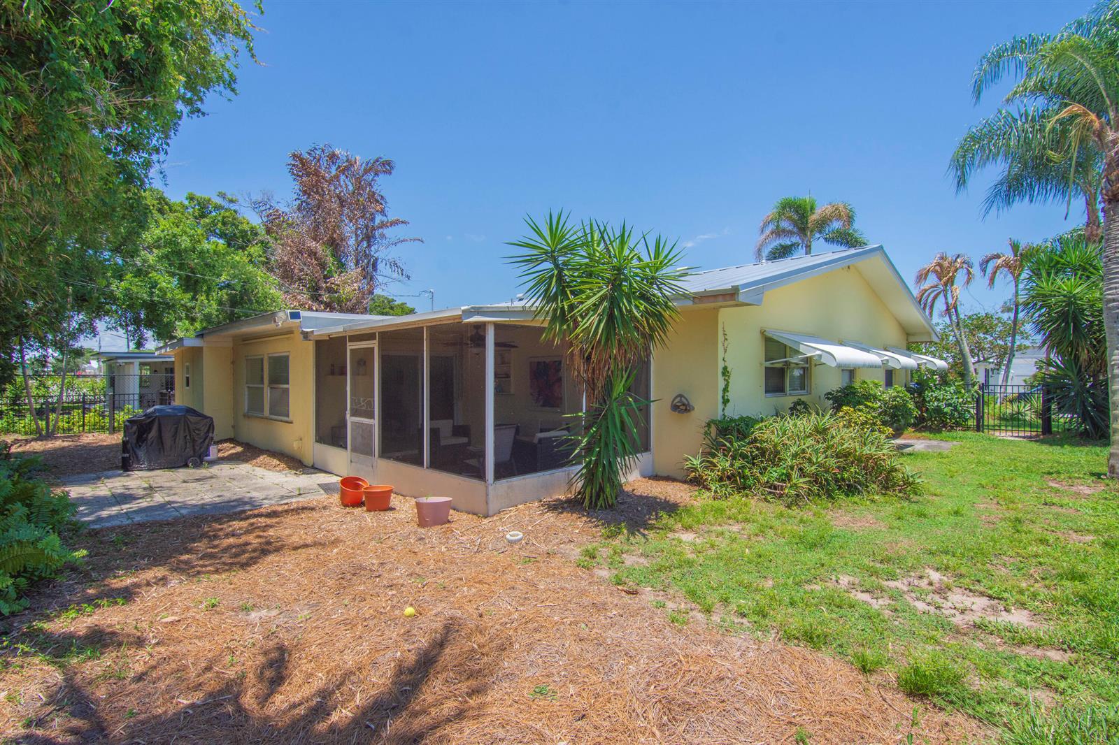 A yellow house features a screened-in porch, a concrete patio, and a grassy backyard — 475 19th Place, Vero Beach FL 32960, VERO BEACH, FL