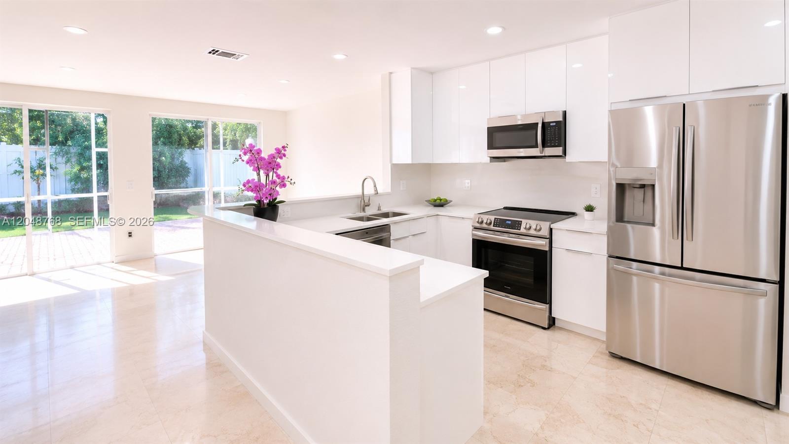 A modern kitchen features white cabinets, stainless steel appliances, and a breakfast bar — 9805 NW 45th Ln, Doral FL 33178, DORAL, FL