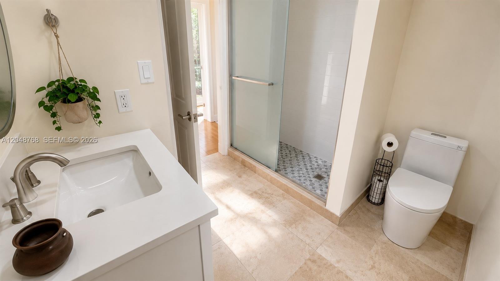A bathroom features a white vanity, a glass-enclosed shower, and a modern toilet — 9805 NW 45th Ln, Doral FL 33178, DORAL, FL