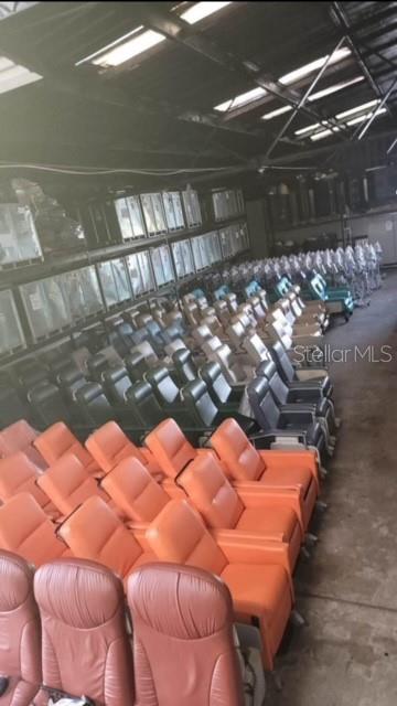 Rows of various colored theater-style reclining chairs are arranged inside a large warehouse space — 424 S DE LEON AVENUE, TITUSVILLE, FL