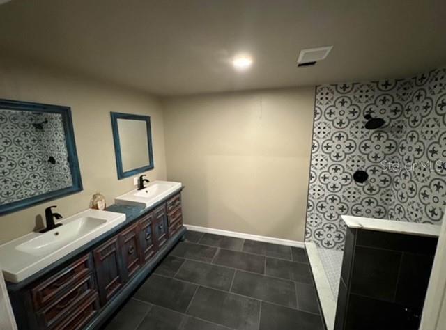 A bathroom features a double vanity with dark wood cabinets and a patterned tile shower — 424 S DE LEON AVENUE, TITUSVILLE, FL